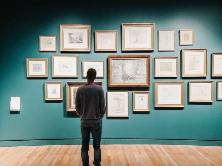 A visitor standing before a wall of framed sketches in a gallery