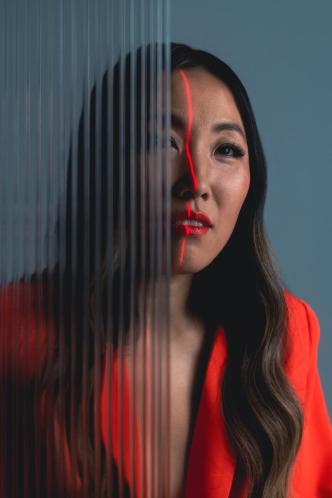 Portrait lit half in red through sheer vertical strings